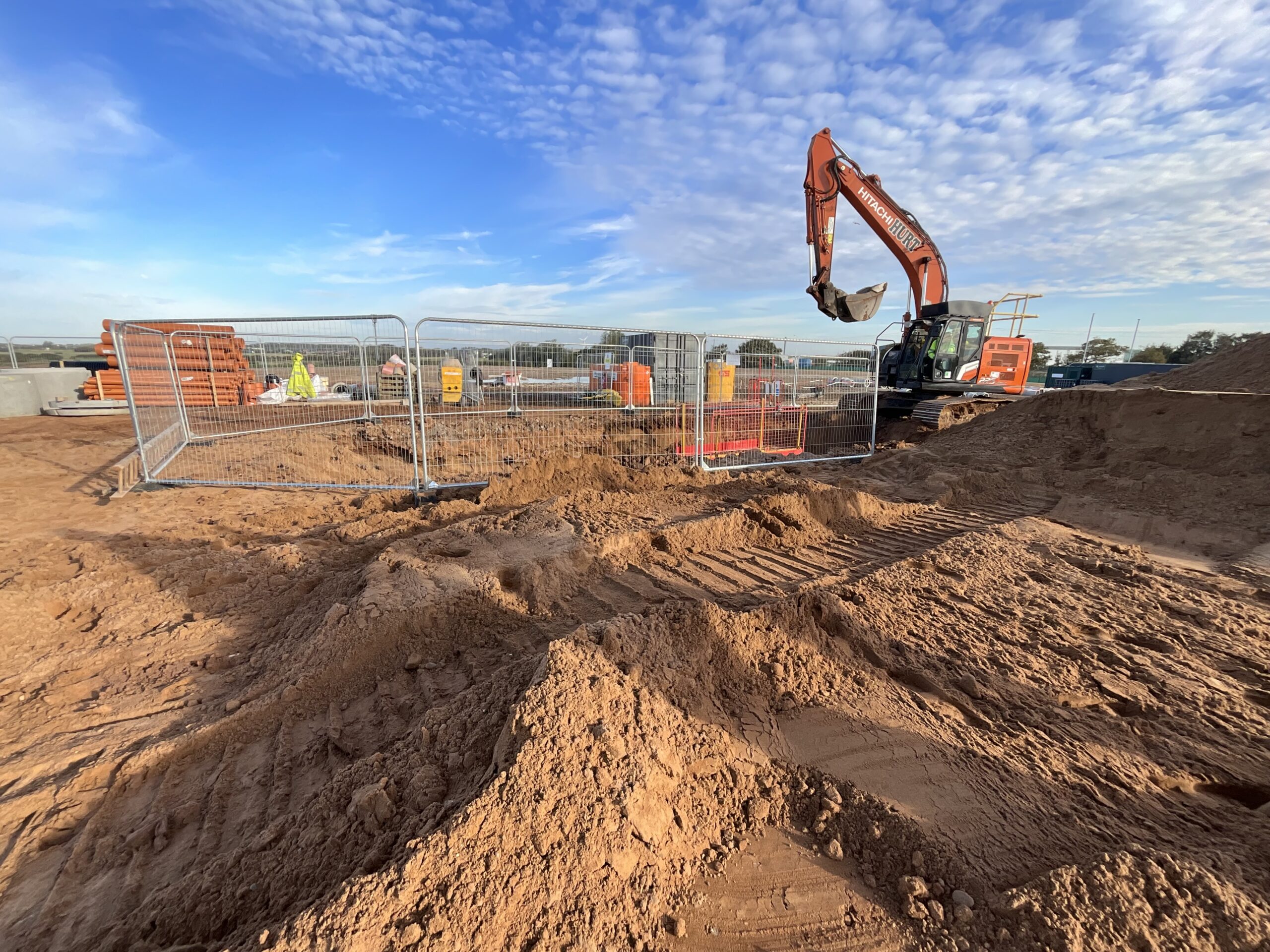 Excavation work taking place on a construction site with plant machinery operating inside a controlled work area.
